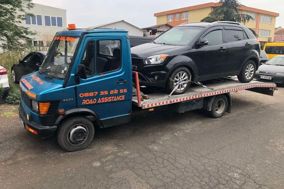 Син платформен влекач ROAD Assistance с натоварен черен джип SsangYong — пътна помощ в Бургас